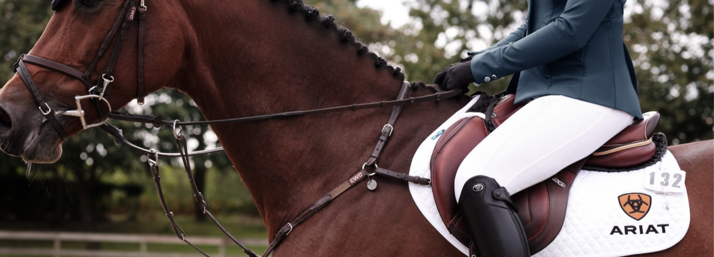 a lady riding a house, white trouser, black boots blue jacket.