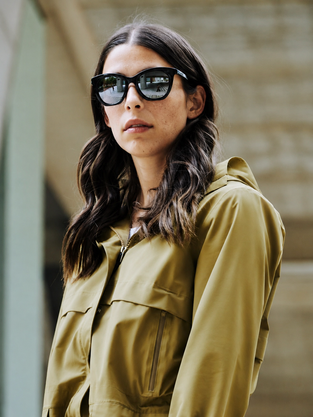 Woman wearing Bolle sunglasses and a green jacket with a blurred background