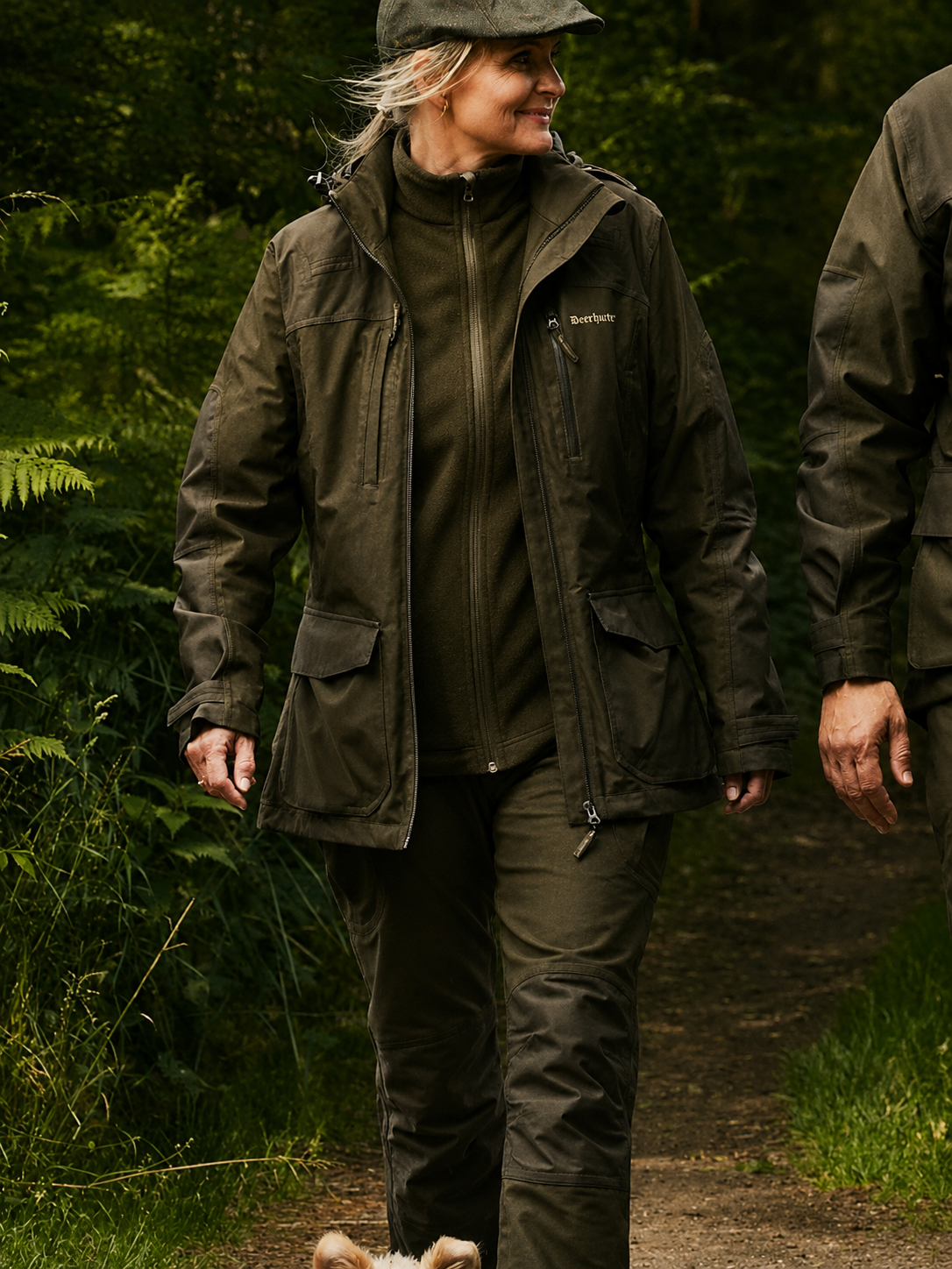 Person wearing a green jacket and hat walking in a forest
