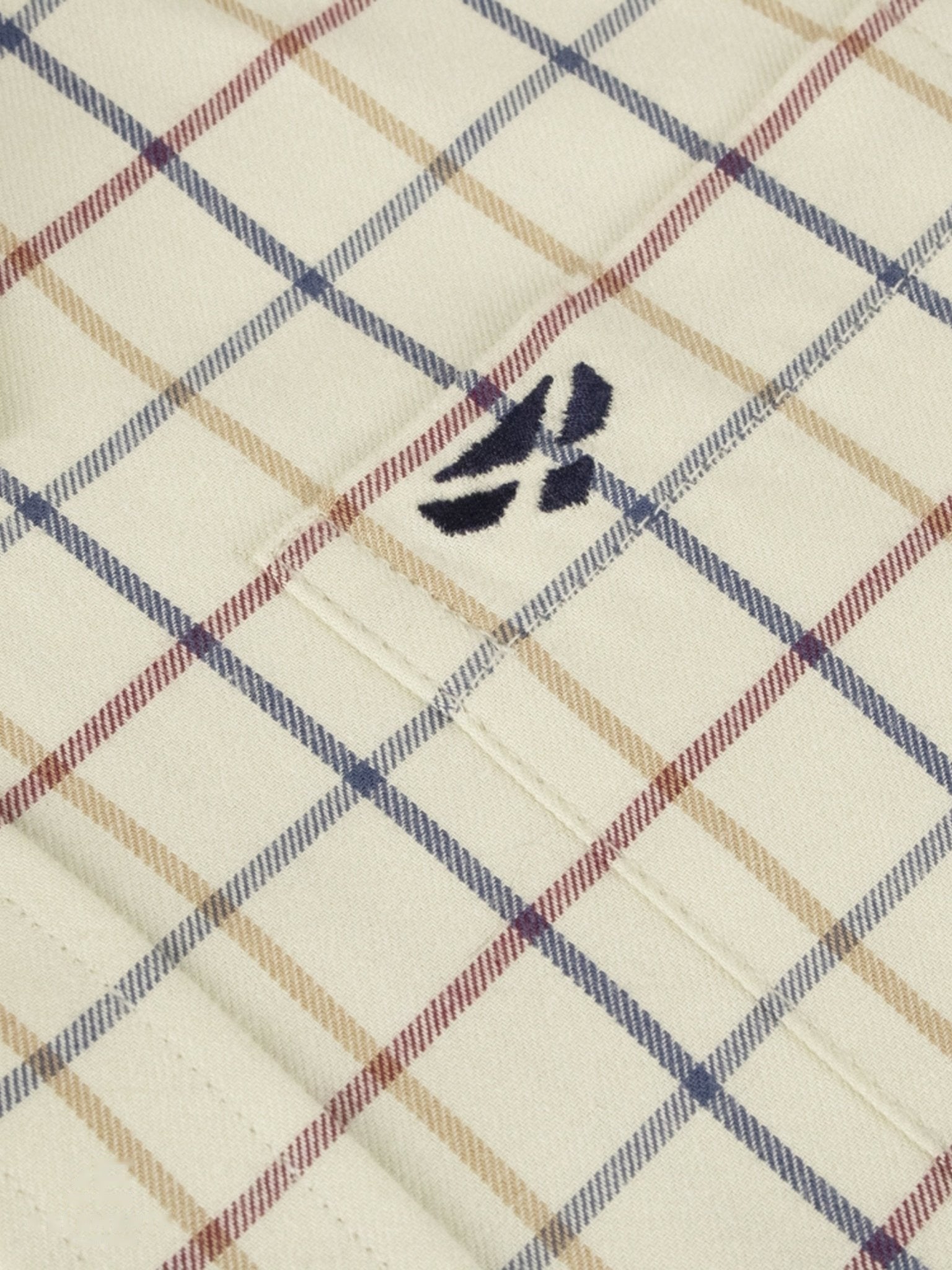 Plaid fabric with a hoggs of fife emblem on a beige chequered background