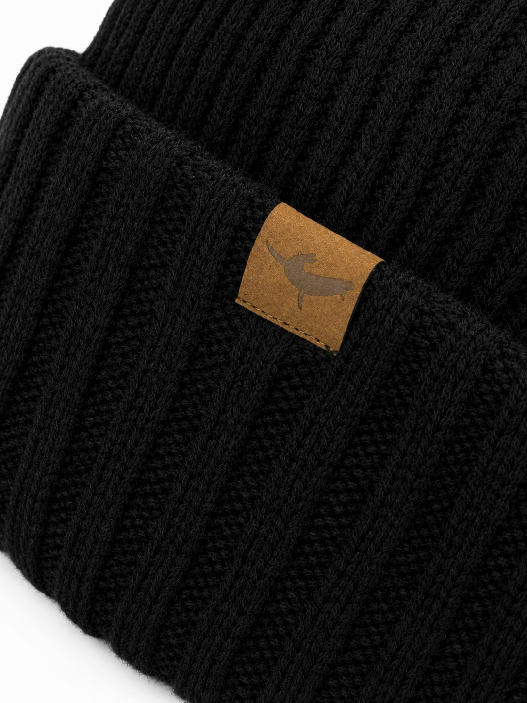 Black knit beanie with a brown leather patch featuring a logo on a white background