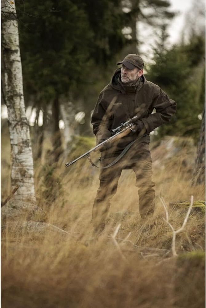 a man that is hunting for deer in the woods wearing all green.