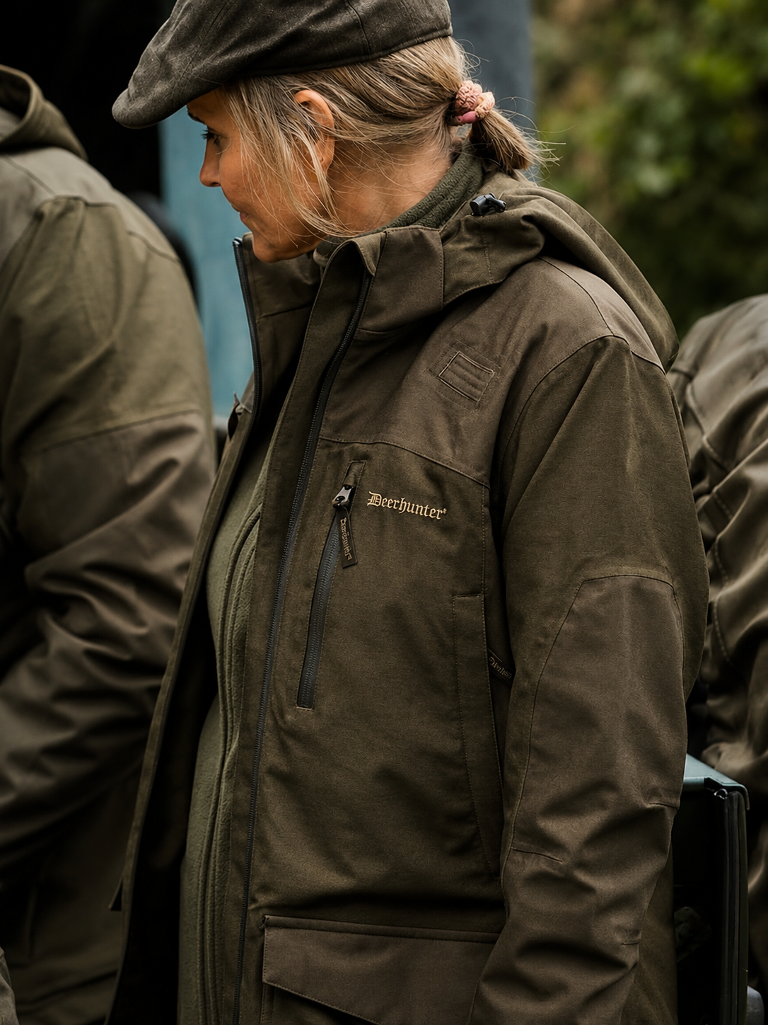 Person wearing a brown jacket with 'Deerhunter' branding outdoors.