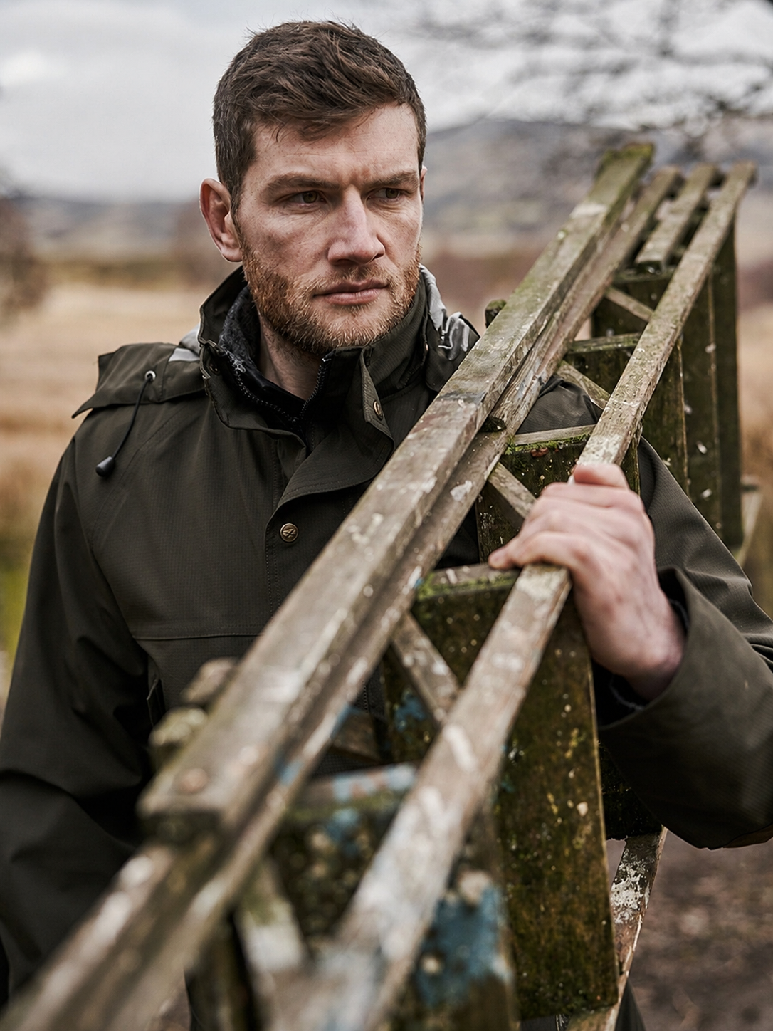 Man holding a wooden ladder in a natural setting