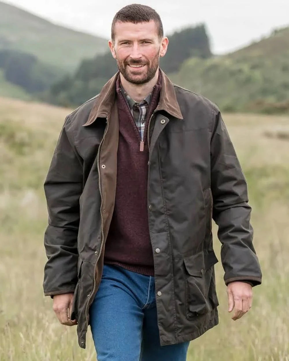Man wearing a brown farming jacket, in a countryside setting.
